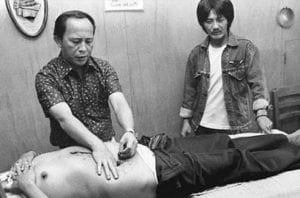 Photograph of Agpaoa placing his hands on the abdomen of a male patient.